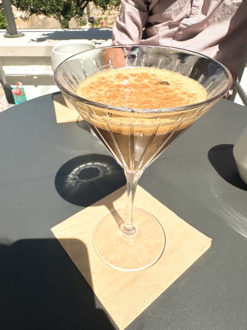 Iced coffee in a martini glass on a café table in the sun in Alberobello