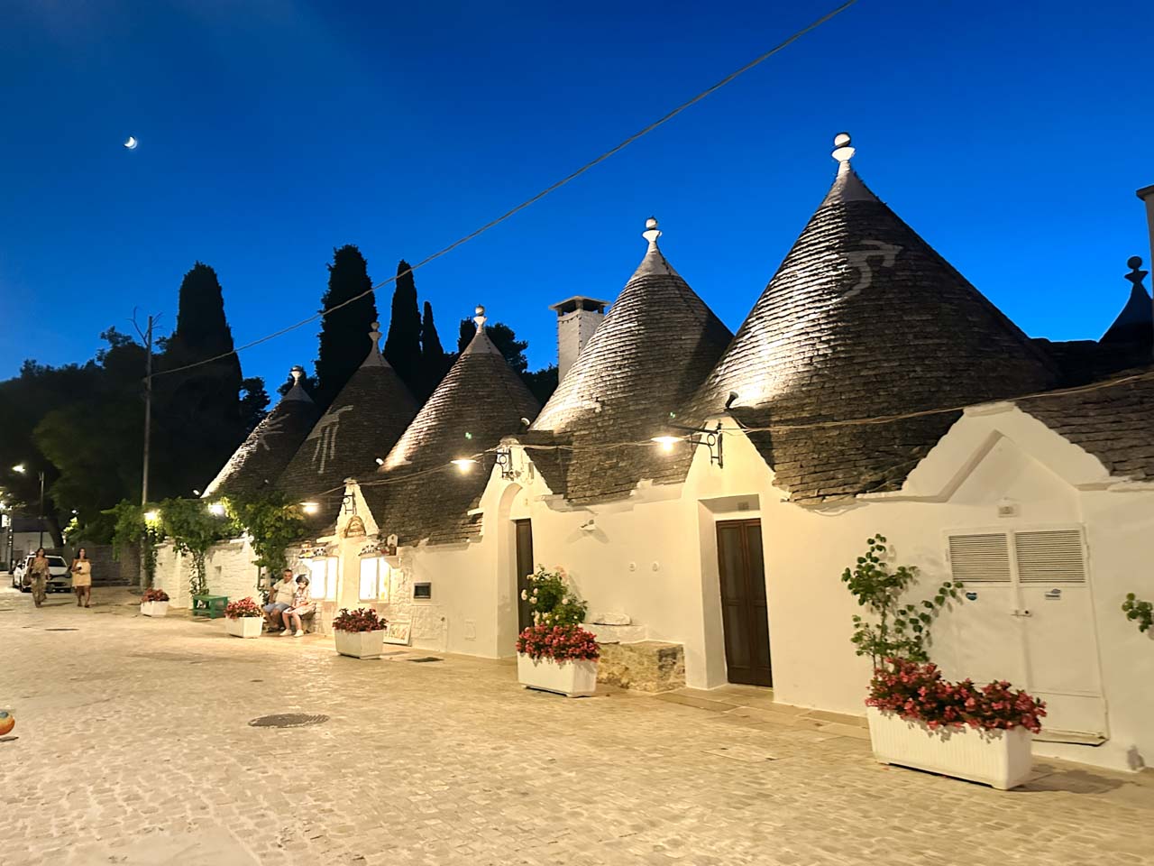 Traditional trulli illuminated at night along a quiet street in Alberobello