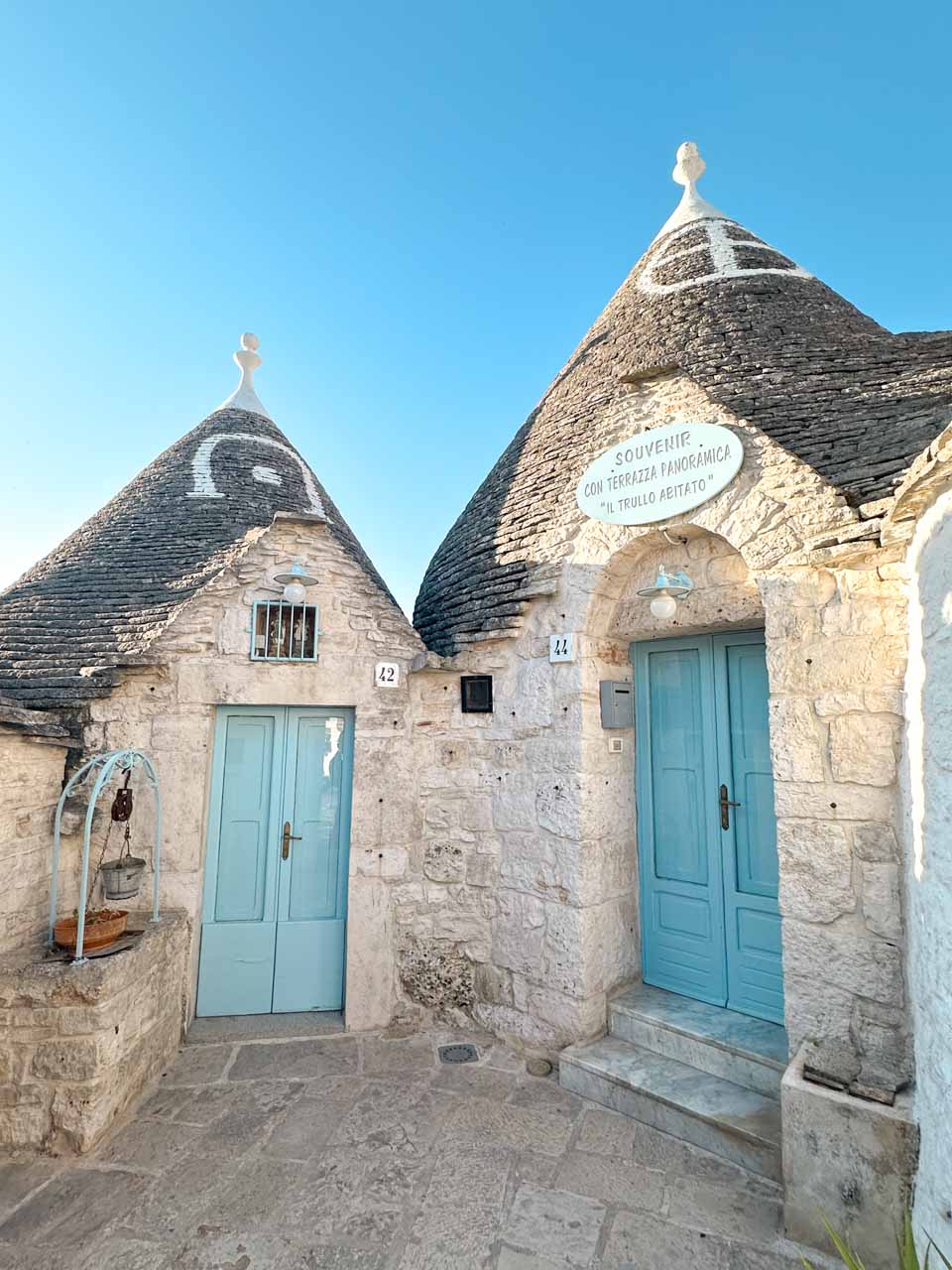 Two trulli houses with blue doors and traditional stone cone roofs in Alberobello, Italy