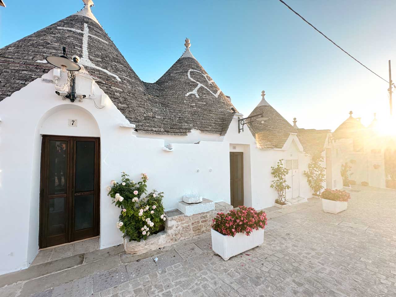White trulli houses with flower boxes and warm evening light in Alberobello, Italy