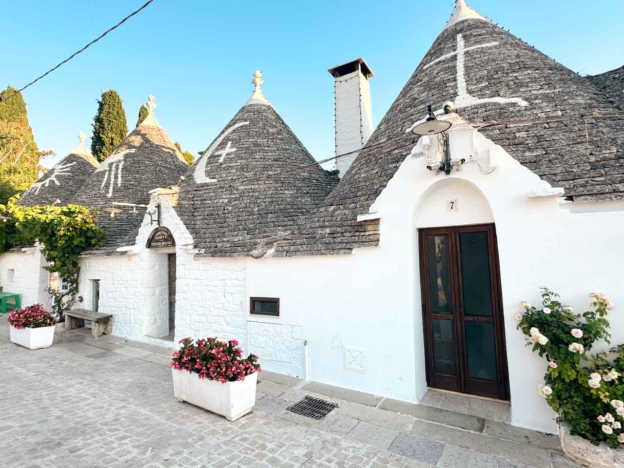 Row of white trulli houses with cone roofs and painted symbols in Alberobello, Italy