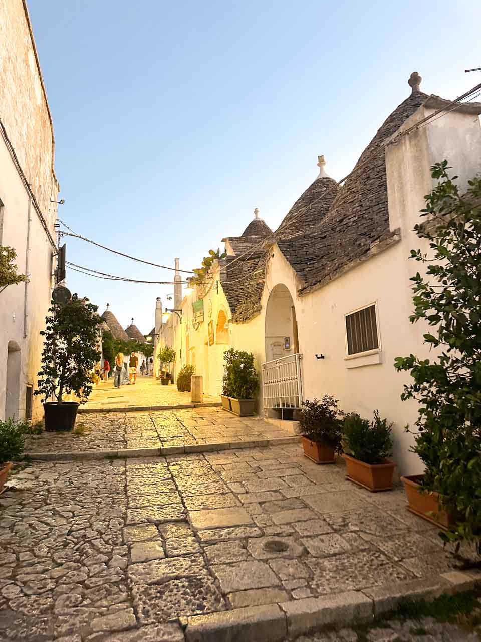 Evening street with white trulli houses glowing under warm lights