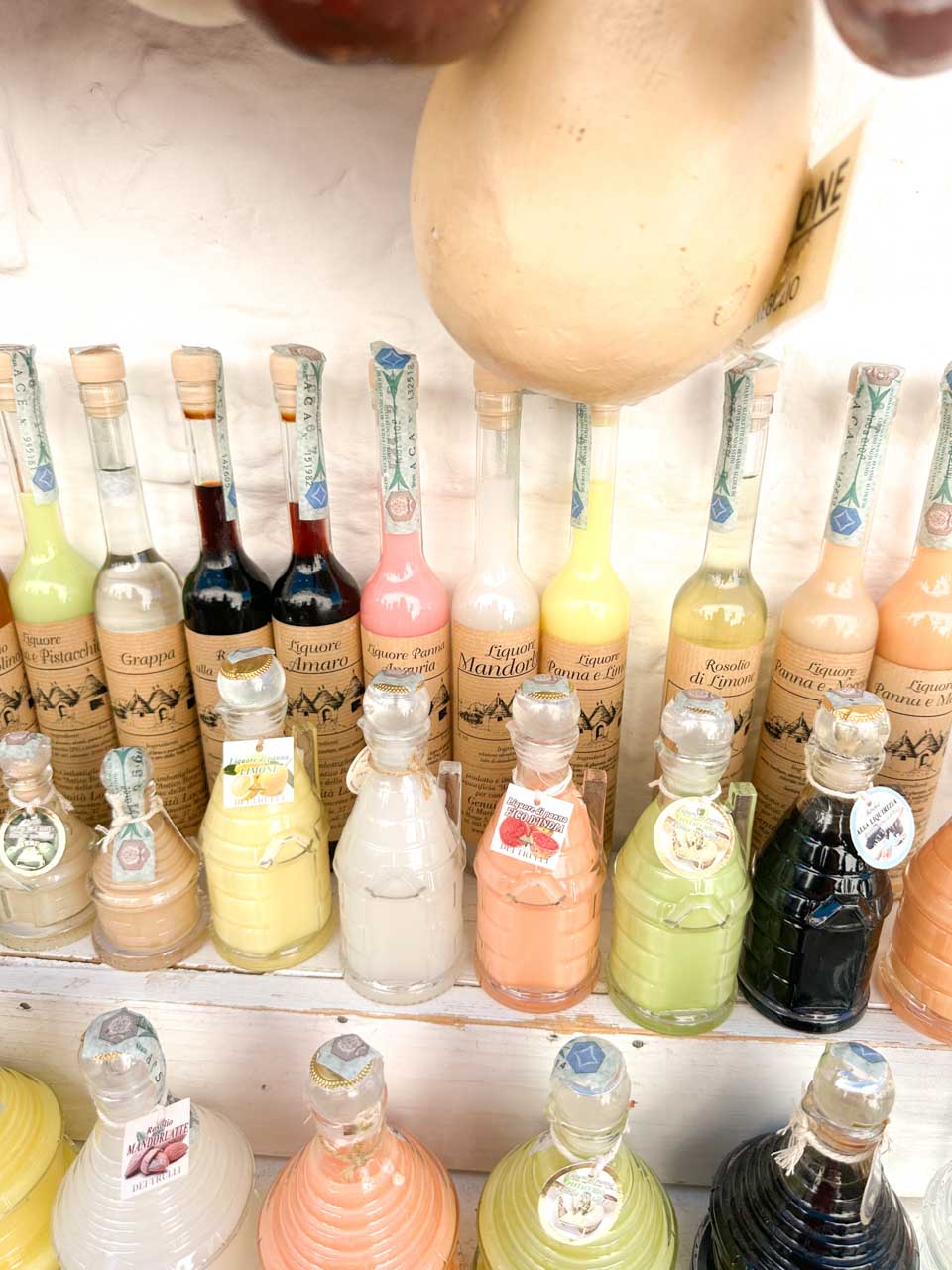 Colourful bottles of local liqueurs lined up on a shop shelf in Alberobello, Italy