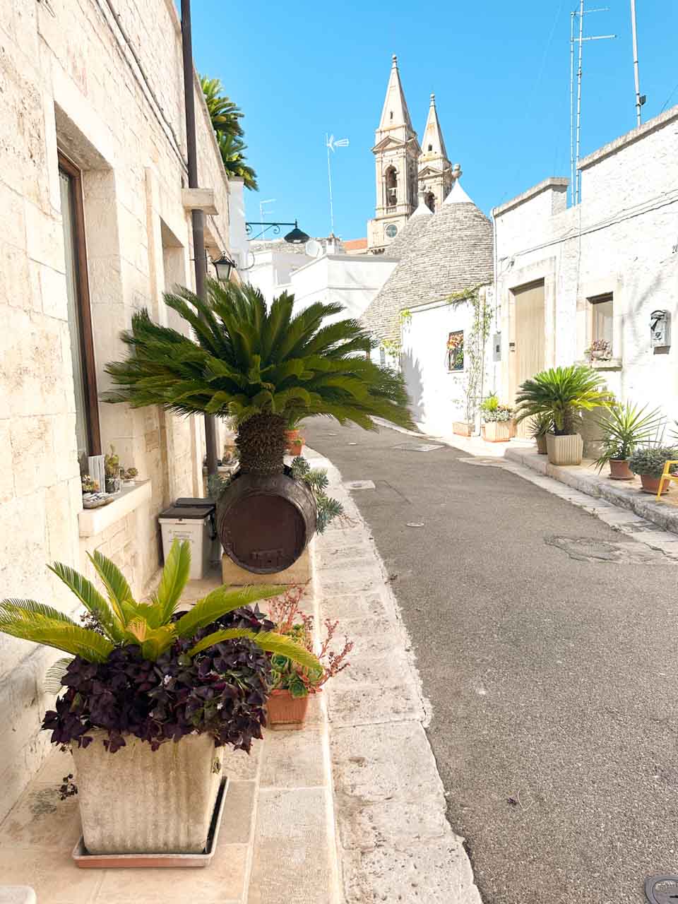 Quiet street lined with trulli houses and the Church of Saints Cosmas and Damian in the background