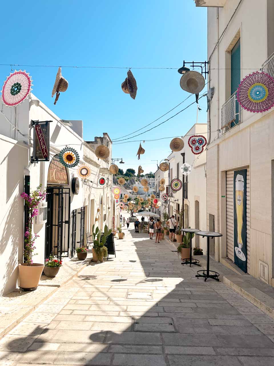 Decorated street with hanging straw hats and colourful crochet ornaments in Alberobello