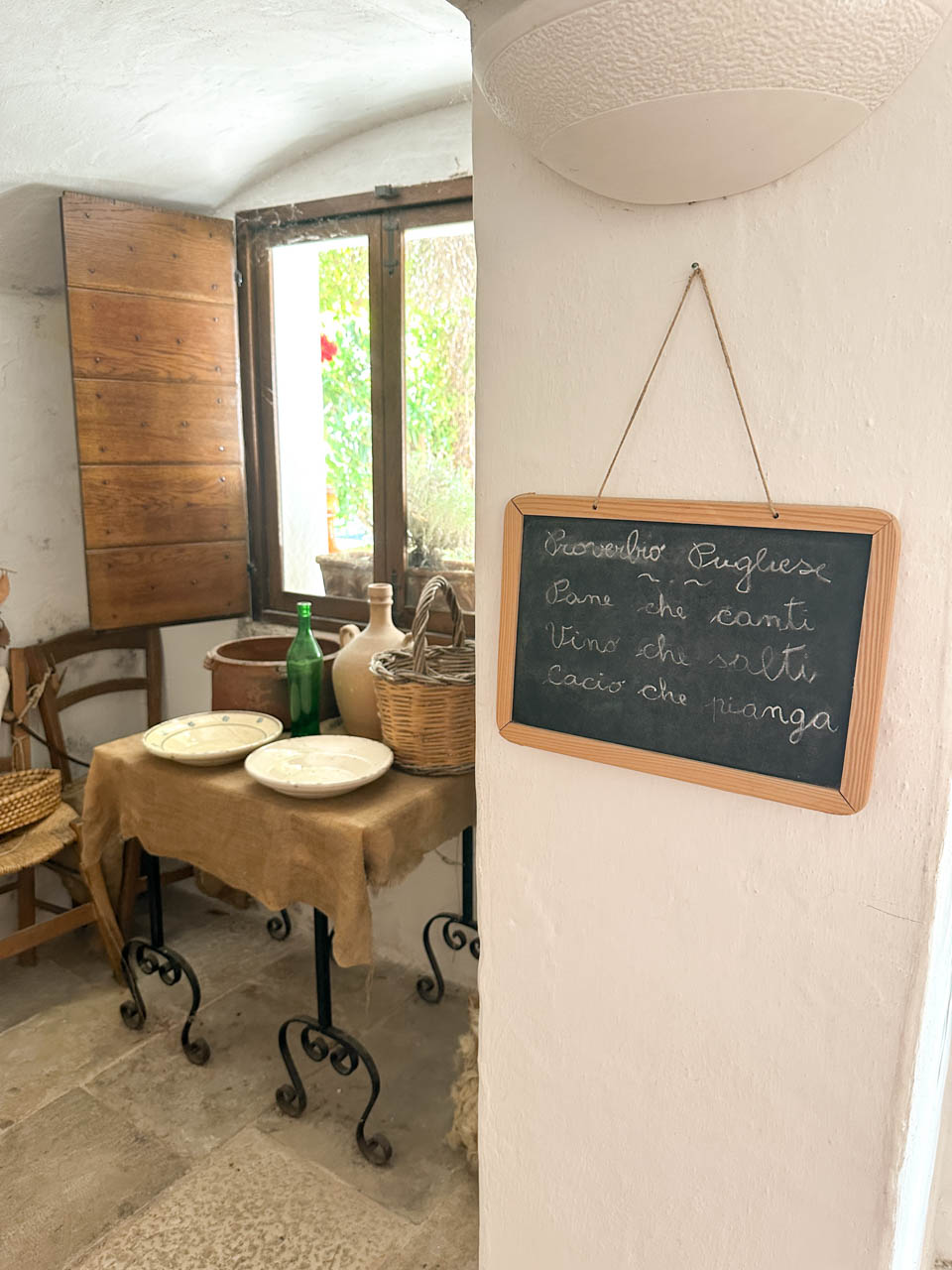 Traditional trullo interior with rustic furnishings and a handwritten Puglian proverb