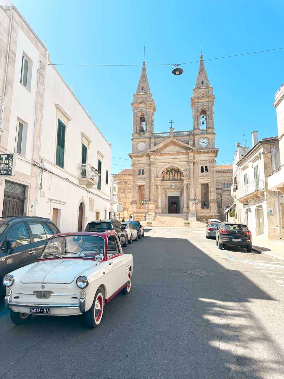 Vintage car parked outside the Basilica of Saints Cosmas and Damian in Alberobello