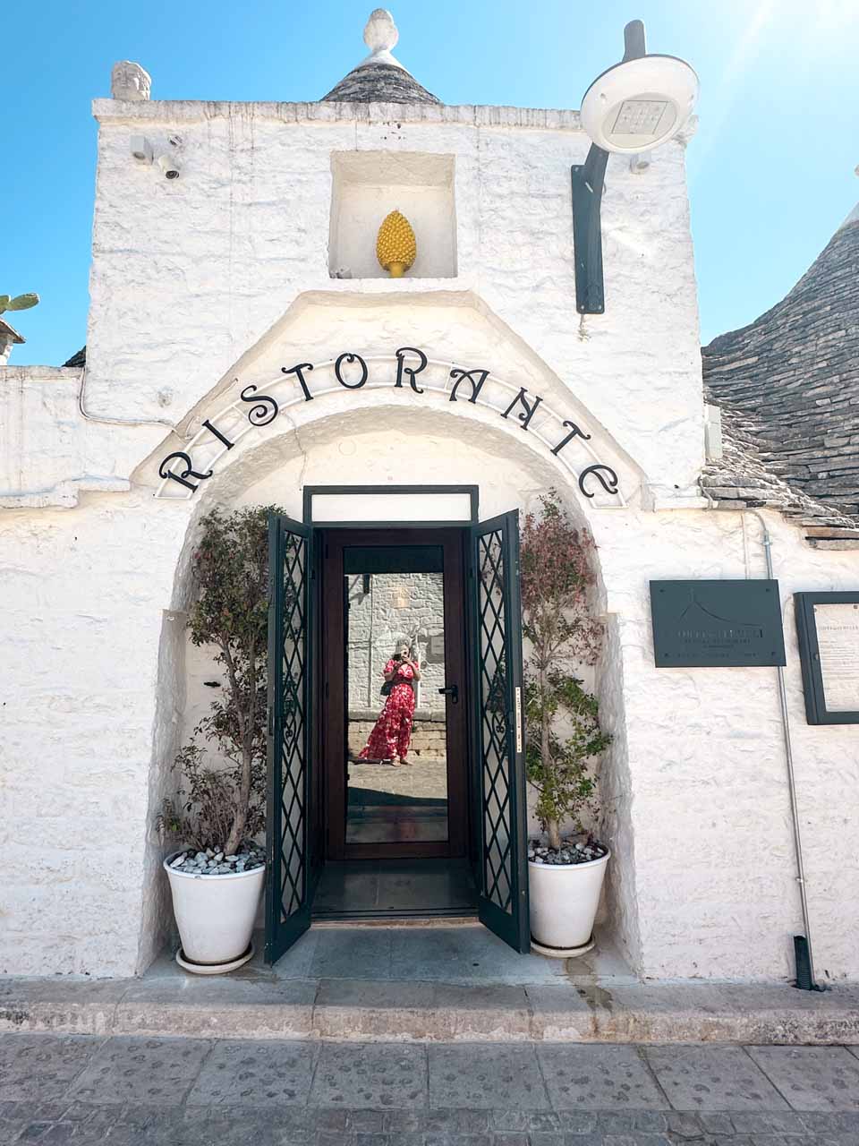 Entrance to the Corte dei Trulli restaurant in Alberobello with a reflection in the glass door