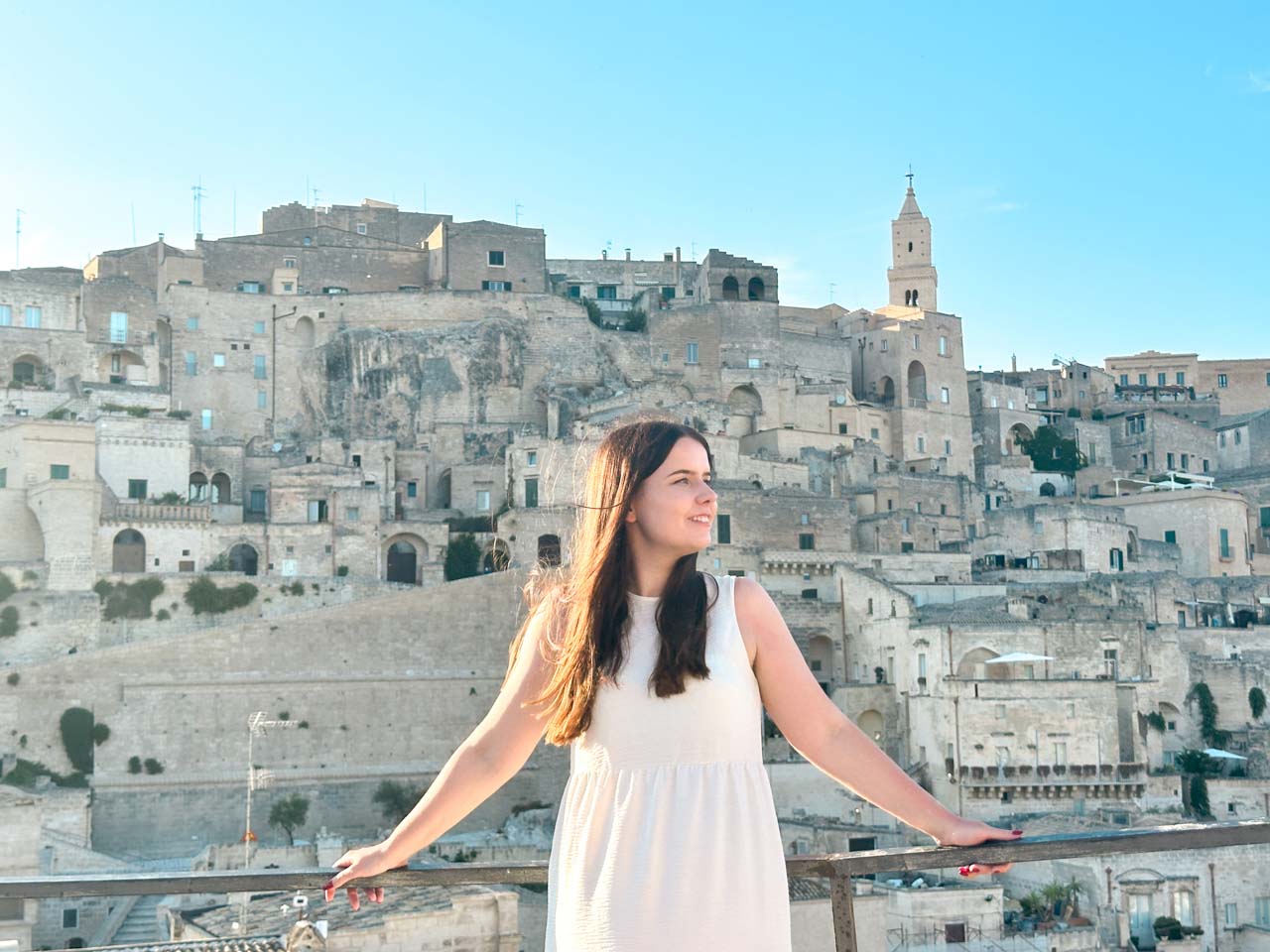 A woman in a white dress standing on Piazza Madonna de Idris with a view over the Sassi of Matera