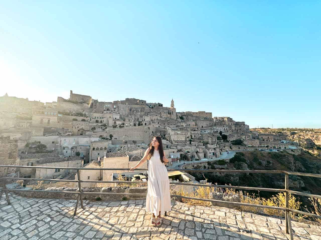 A woman in a white maxi dress overlooking the Sassi district from a viewpoint in Matera, Italy