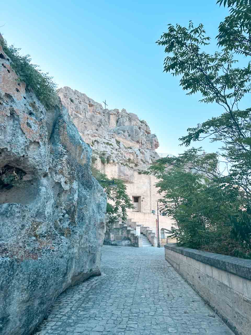 Cobbled path winding past limestone cliffs and cave dwellings in Matera, Italy