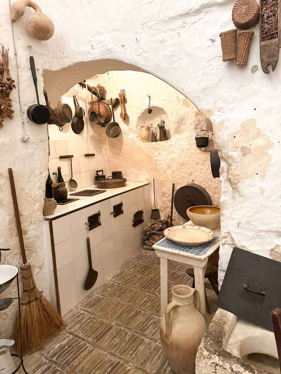 Traditional kitchen with cooking utensils and stone walls inside Casa Grotta in Matera