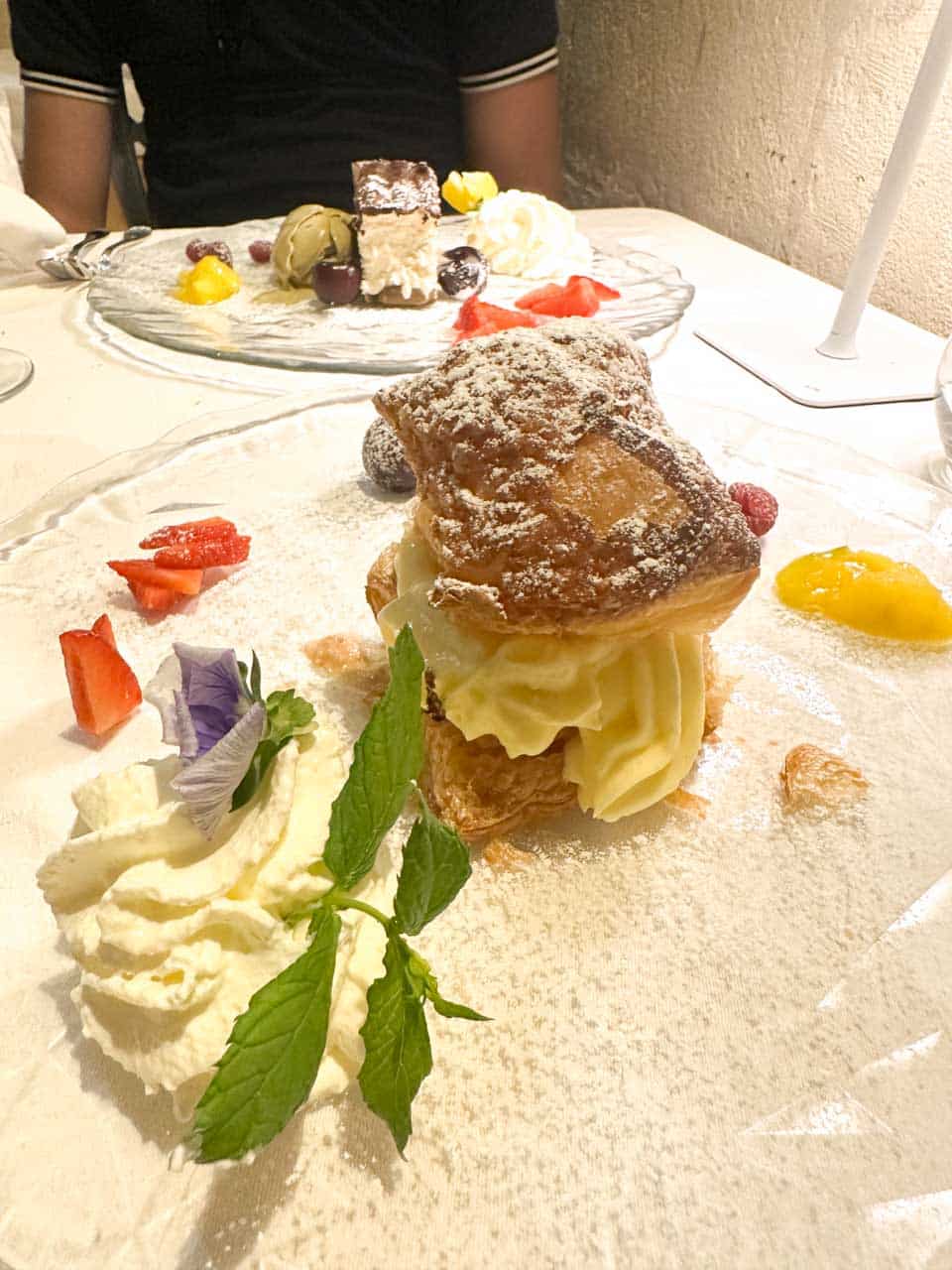 A mille-feuille dusted with icing sugar and served with fruit and whipped cream at San Biagio Ristorante in Matera