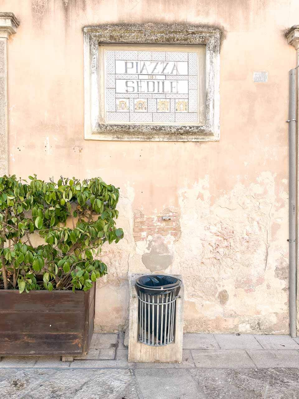 Ceramic street sign for Piazza del Sedile on a weathered stone wall in Matera, Italy