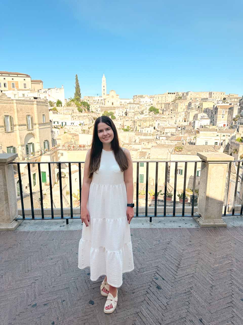 A woman standing at the Belvedere dei Tre Archi viewpoint in Piazza Vittorio Veneto with the Sassi di Matera in the background