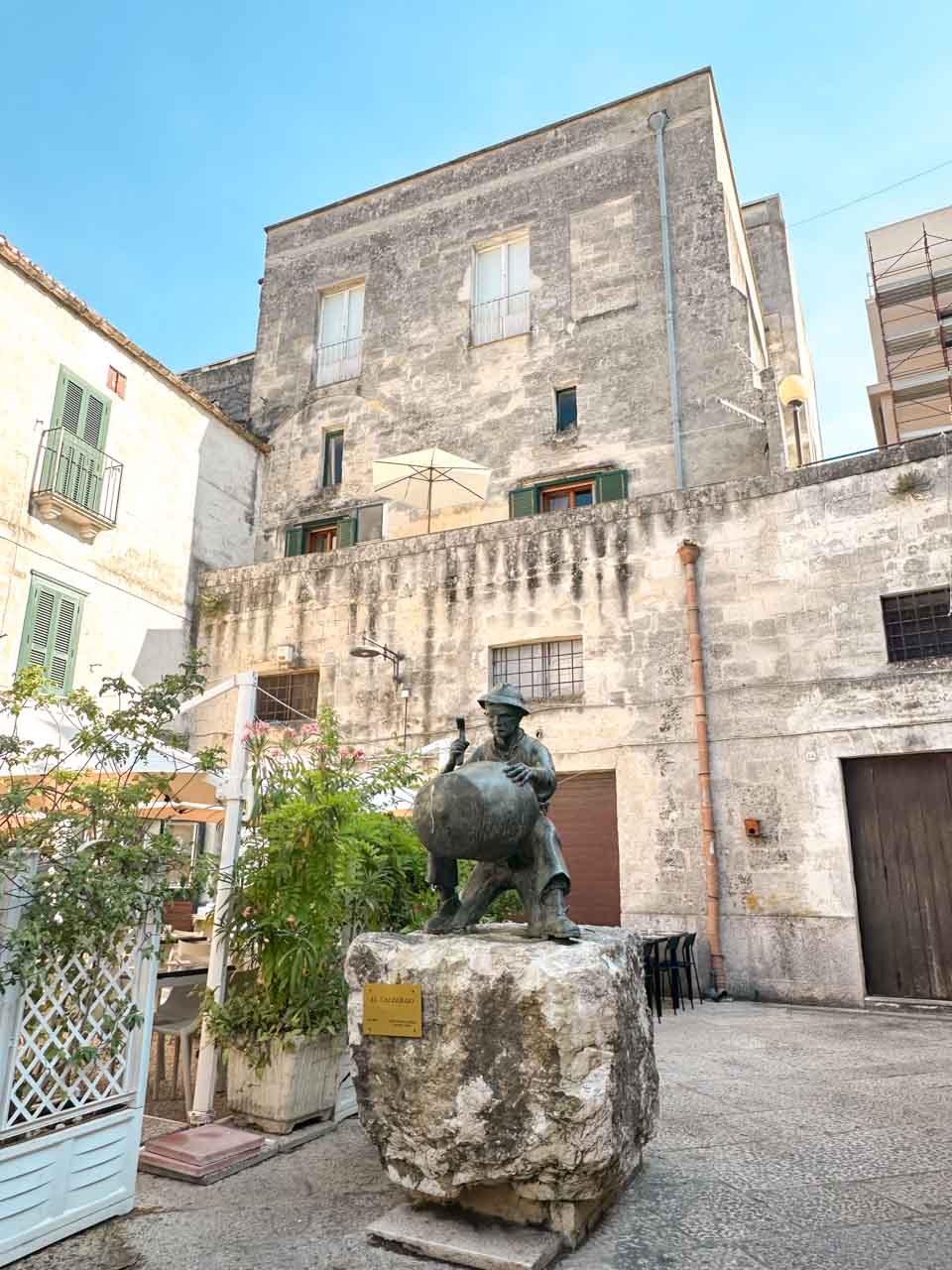 The bronze statue of a traditional coppersmith in a small square in Matera
