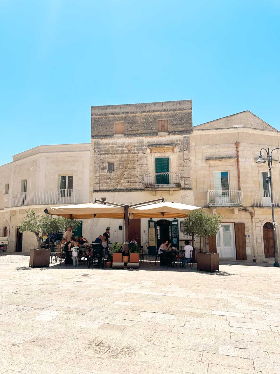 Outdoor tables beneath parasols outside Gahv&egrave; coffee & drink in Matera's historic centre