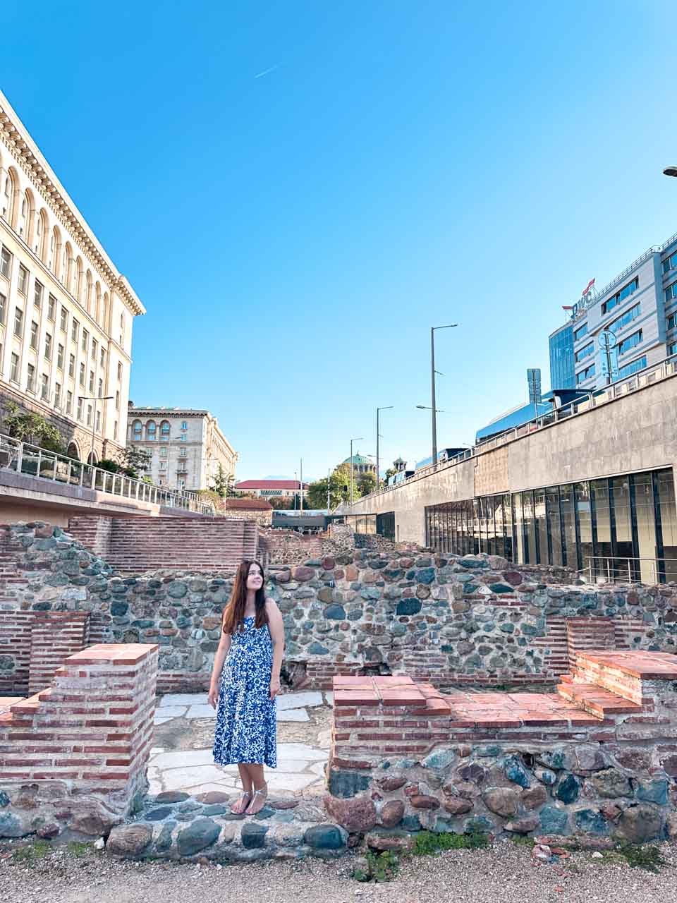 Woman in a blue and white dress standing among the ancient Roman ruins of Serdica in Sofia