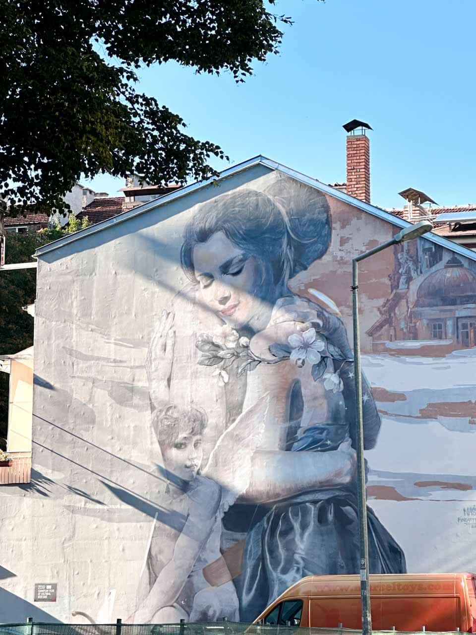Large mural of a woman and child painted on the side of a building in Sofia