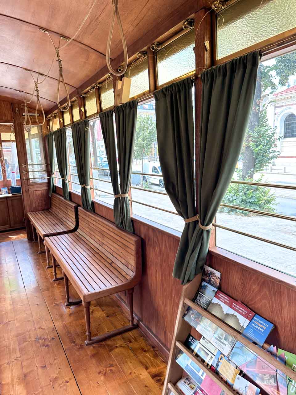 Wooden benches and green curtains inside a vintage Sofia tram