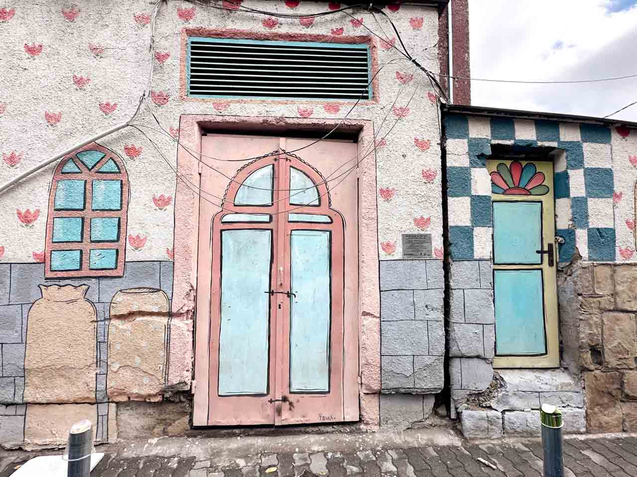 Pastel-coloured street art painted around doors and windows in Sofia