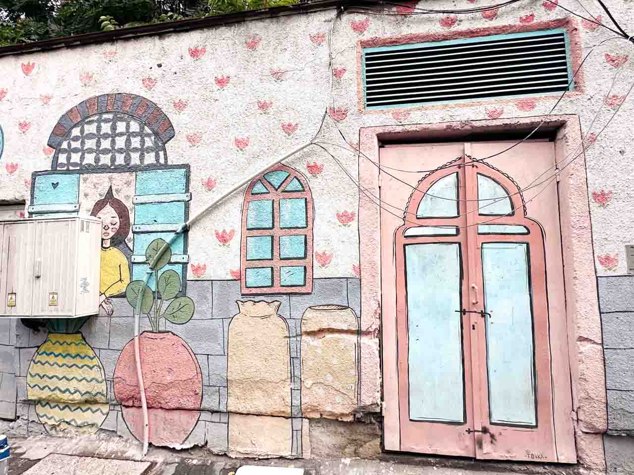 Colourful street art with painted windows, oversized vases, plants, and a woman peeking out from behind shutters in Sofia, Bulgaria
