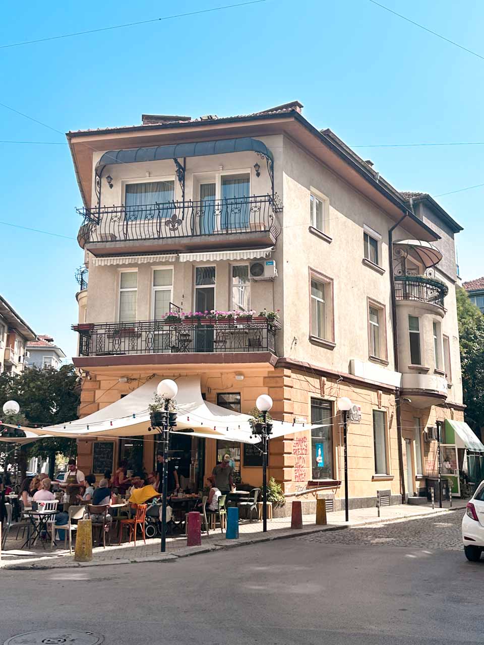 Corner caf&eacute; with outdoor seating beneath the balconies of a residential building in central Sofia, Bulgaria