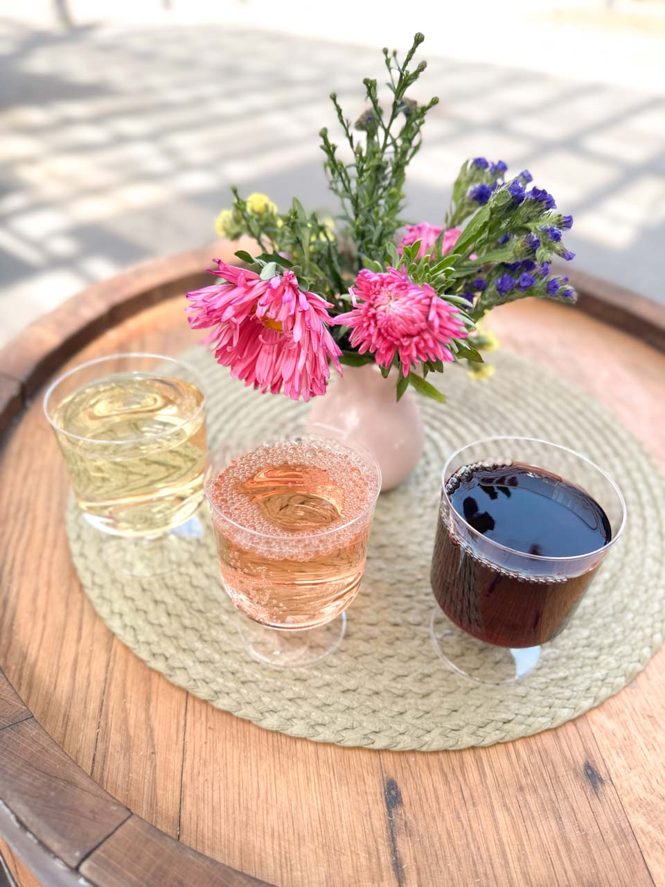 Glasses of white, ros&eacute;, and red wine beside a vase of colourful flowers on a wooden table in Sofia