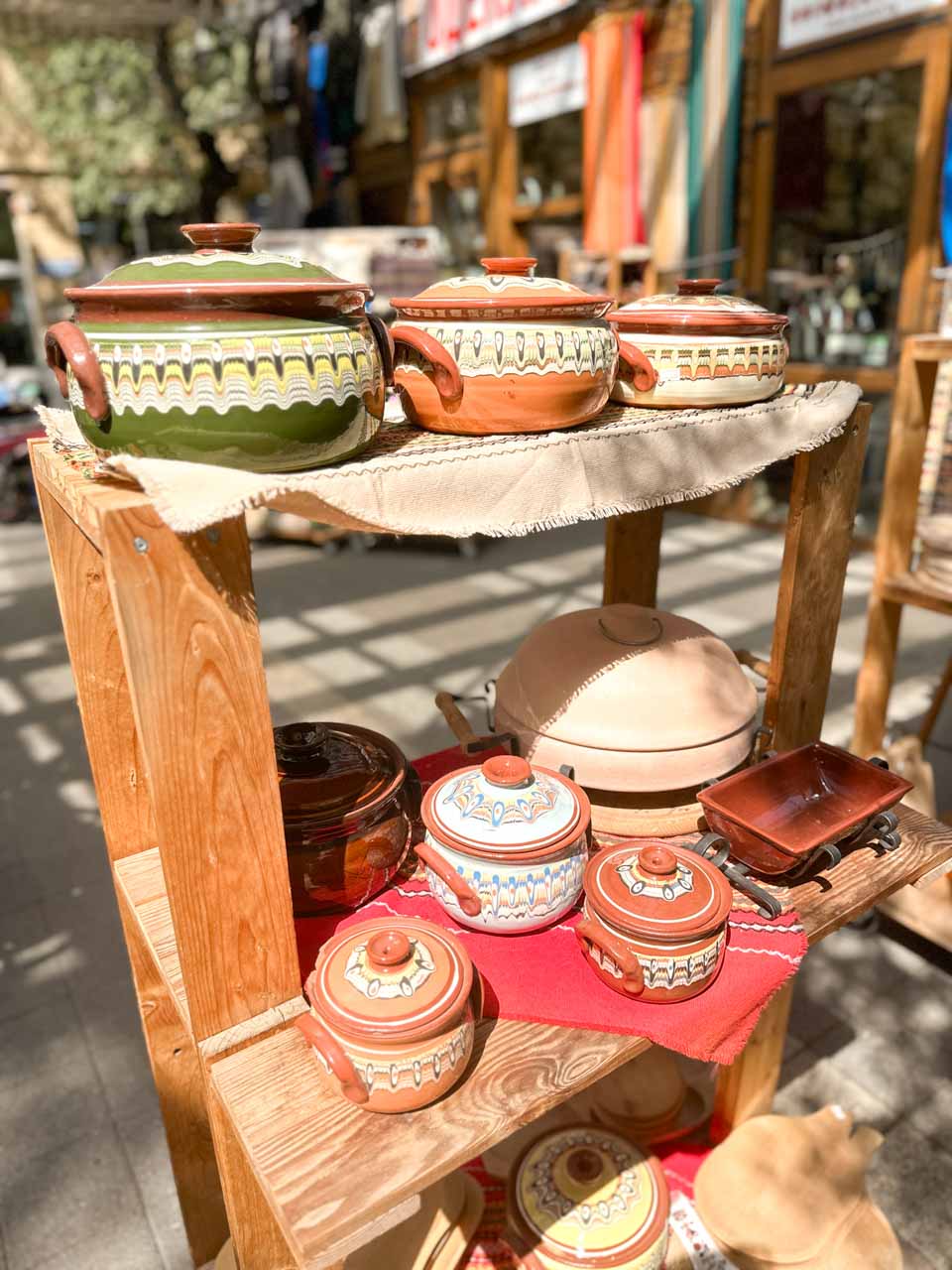 Colourful traditional Bulgarian ceramic pots displayed on wooden shelves at Zhenski Pazar, or Women&rsquo;s Market, in Sofia