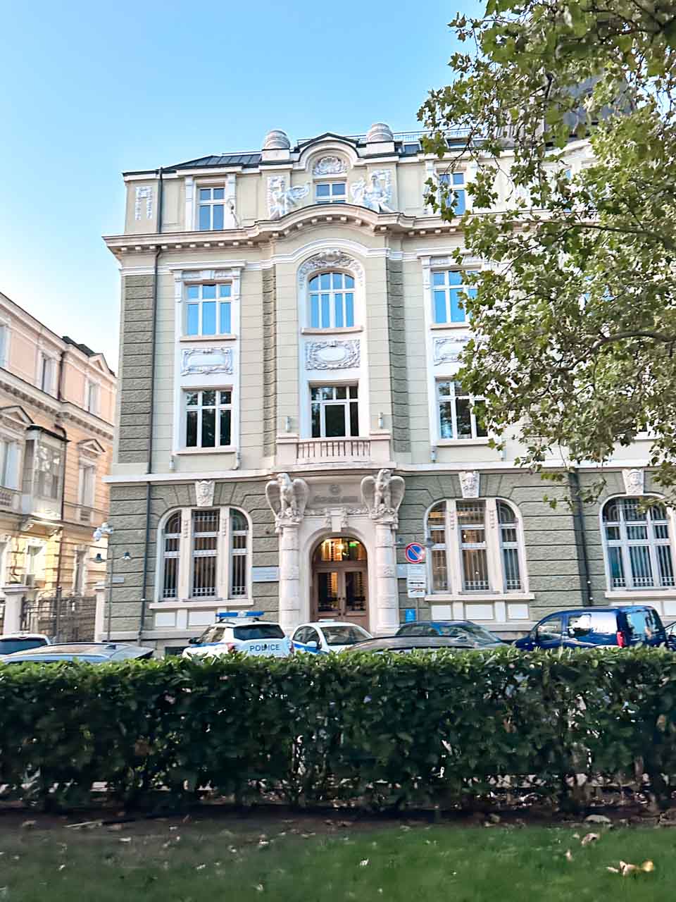 An ornate historic building in central Sofia with decorative stonework, arched windows, and a grand entrance
