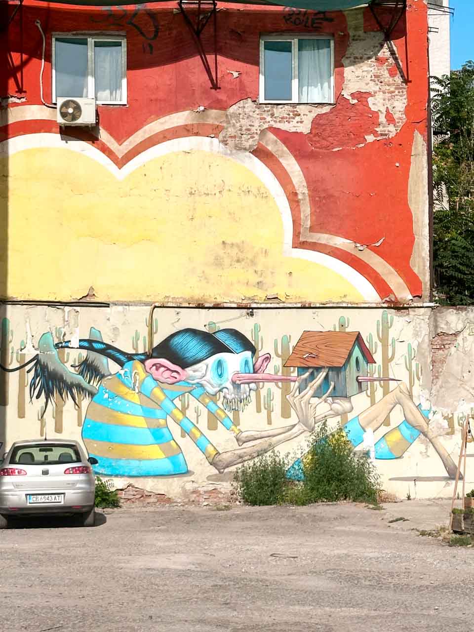 Colourful street art in Sofia showing a surreal winged figure with a long nose, holding a birdhouse