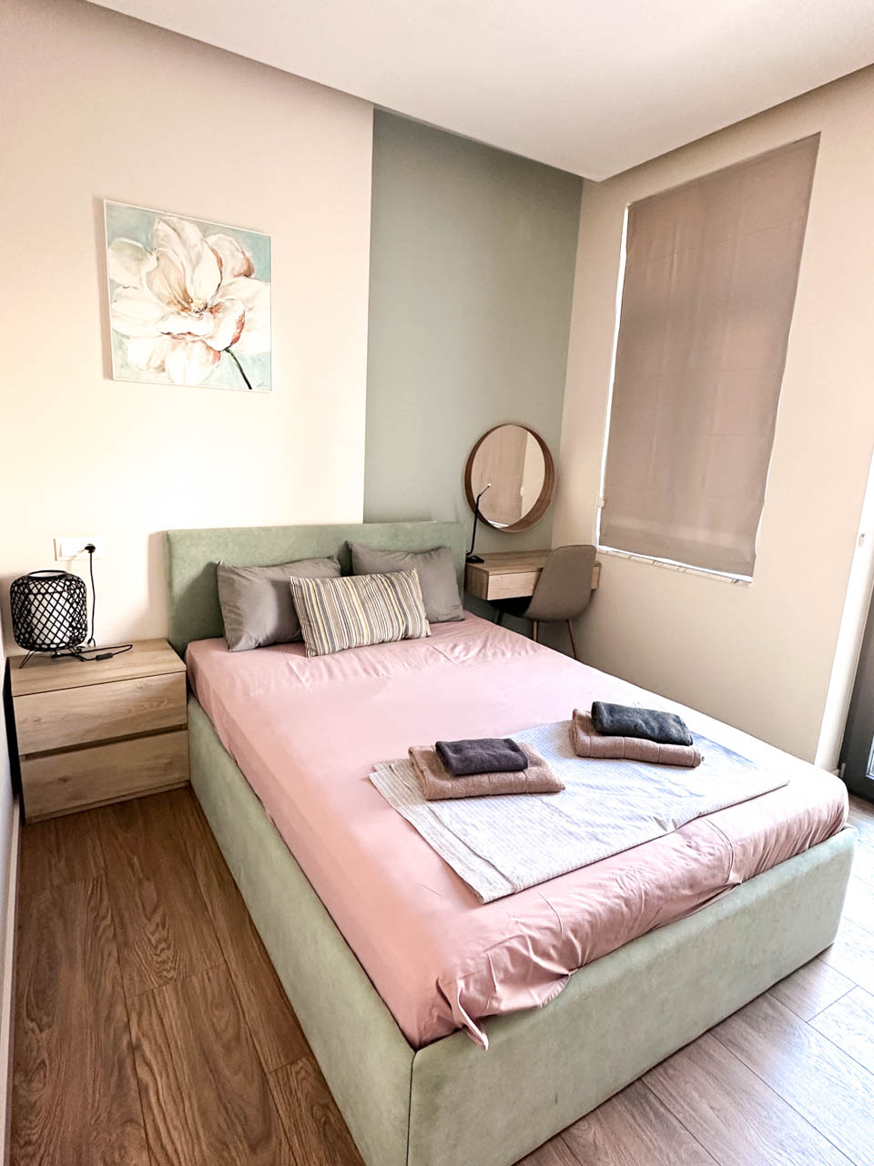 Bedroom in a modern Sofia flat with a double bed, a bedside table, a dressing table, and folded towels