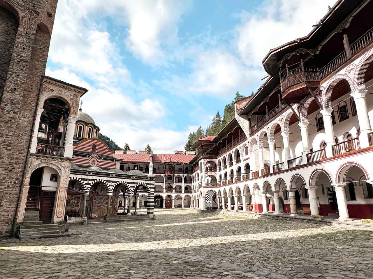 Courtyard of Rila Monastery with the church and surrounding monastery buildings lined with rows of white arches