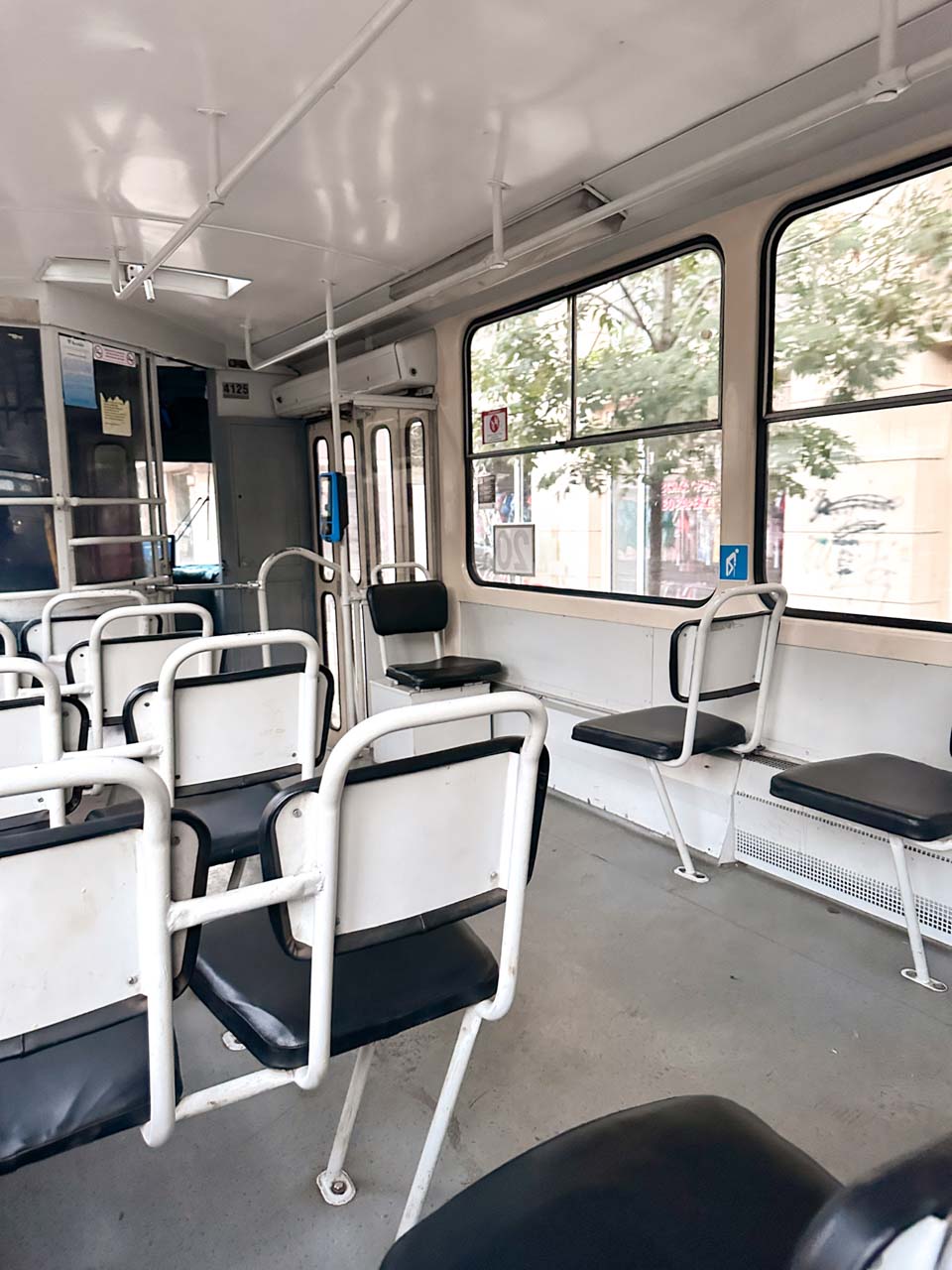 Interior of a tram in Sofia, with rows of white-framed seats and large windows looking out onto the street