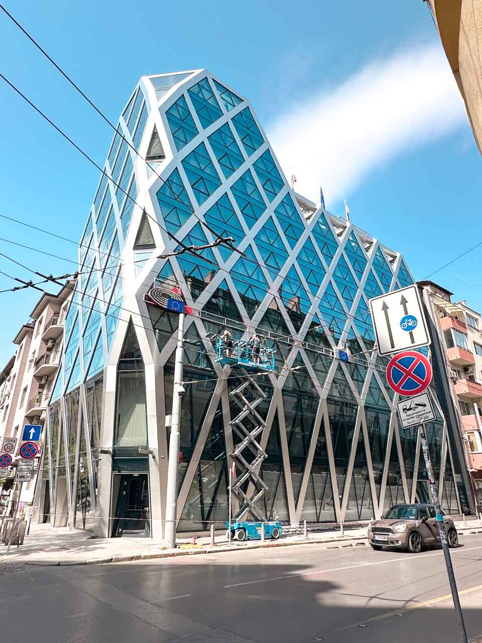 Modern glass office building in Sofia with a geometric white frame across its blue-tinted windows