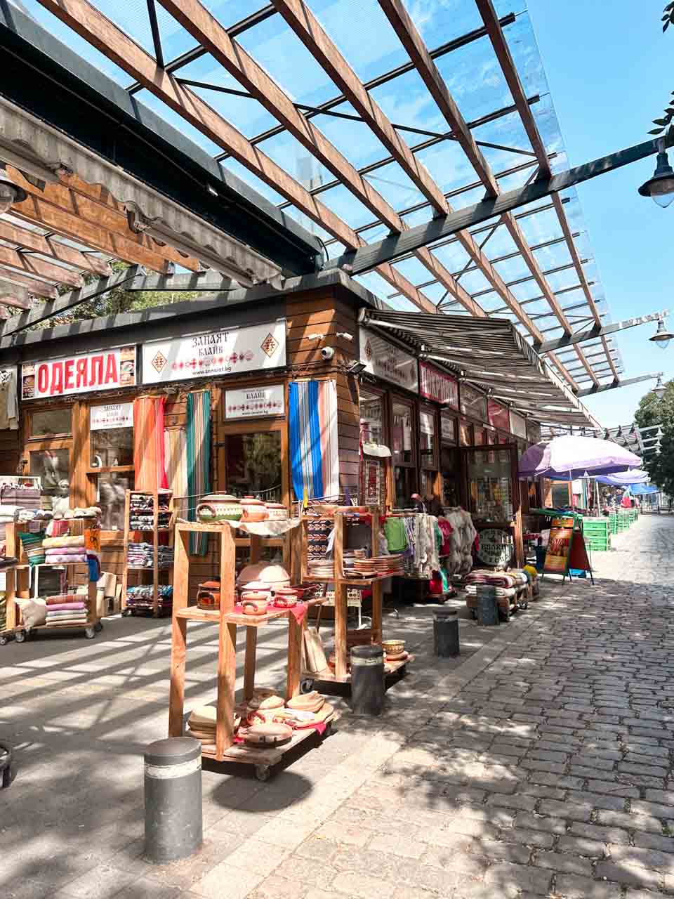 Colourful pottery, textiles, and souvenirs displayed outside shops at the Women's Market in Sofia