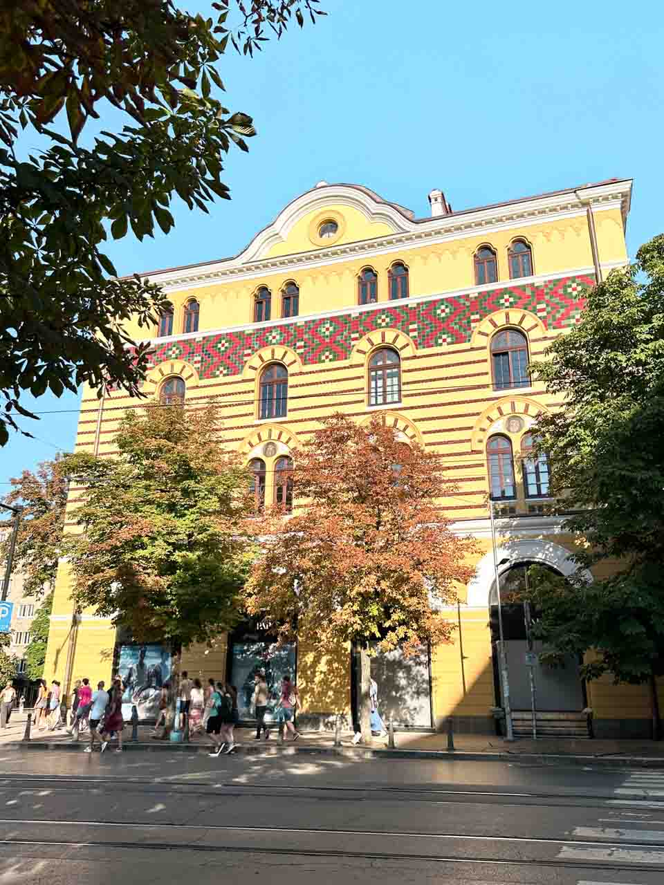 Yellow historic building in central Sofia decorated with colourful geometric patterns above its arched windows