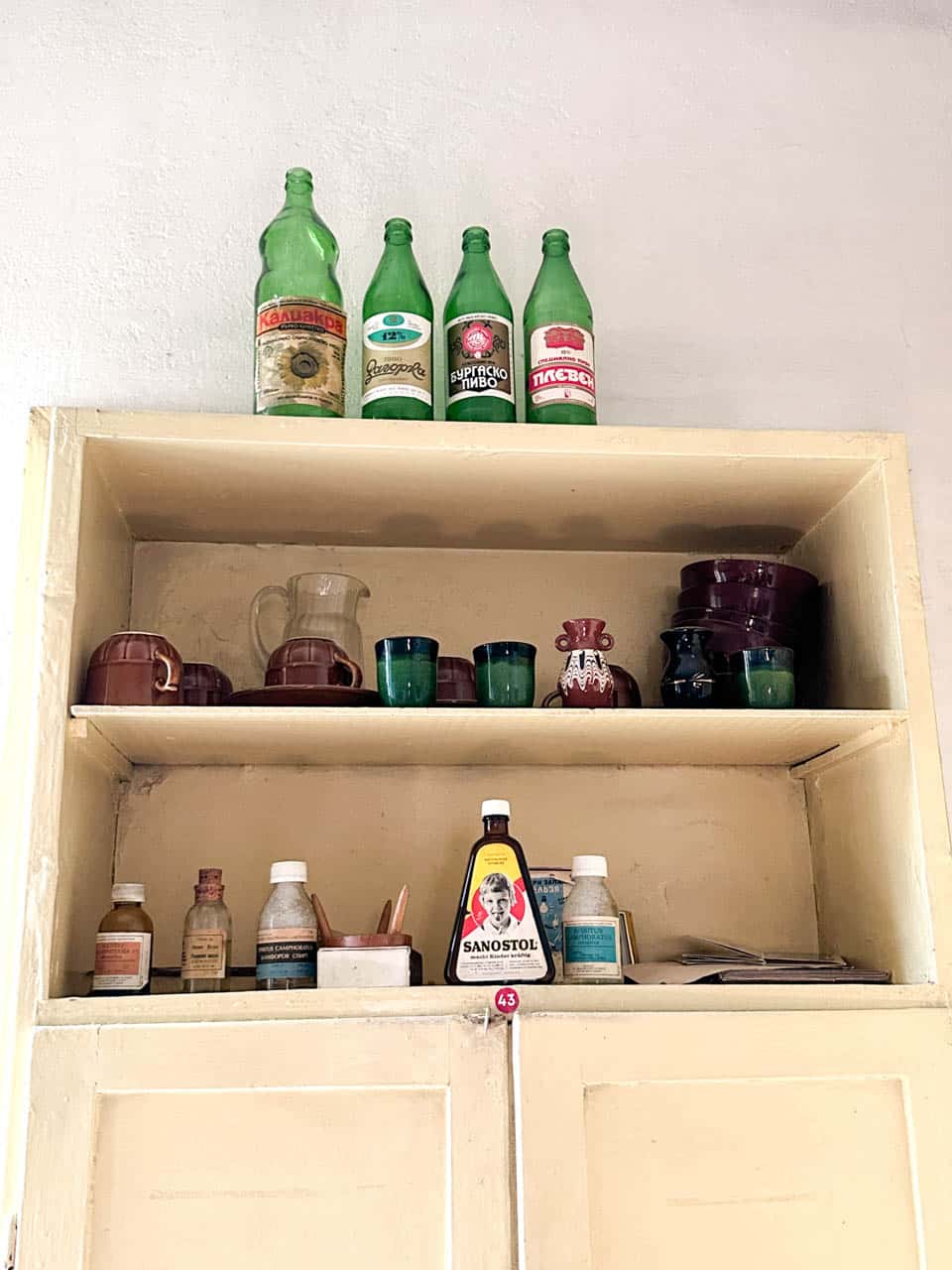 Vintage Bulgarian bottles, cups, and medicines displayed on a cabinet at the Red Flat museum in Sofia