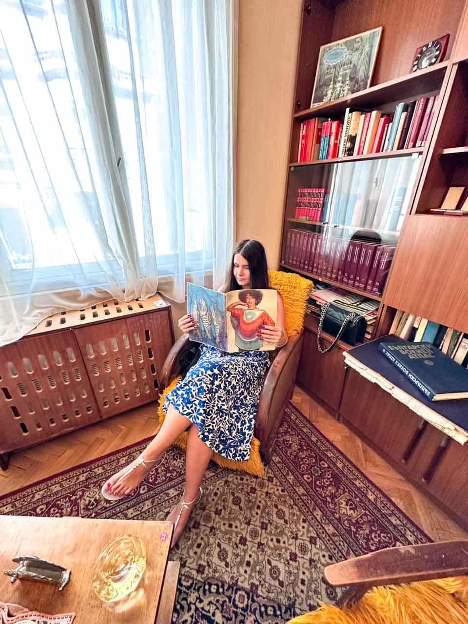Woman reading a vintage magazine in an armchair at the Red Flat museum in Sofia, Bulgaria