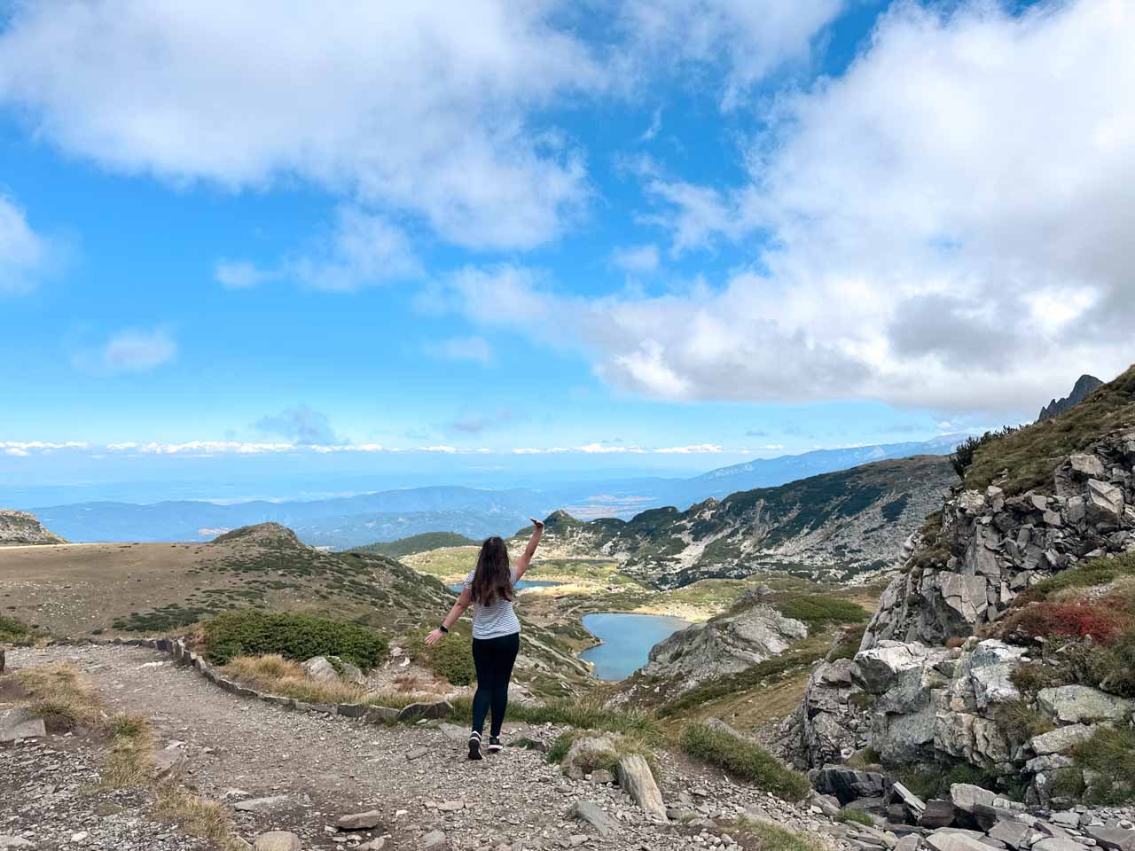 Woman posing with her arms thrown up in happiness above one of the Seven Rila Lakes in Bulgaria&rsquo;s Rila Mountains
