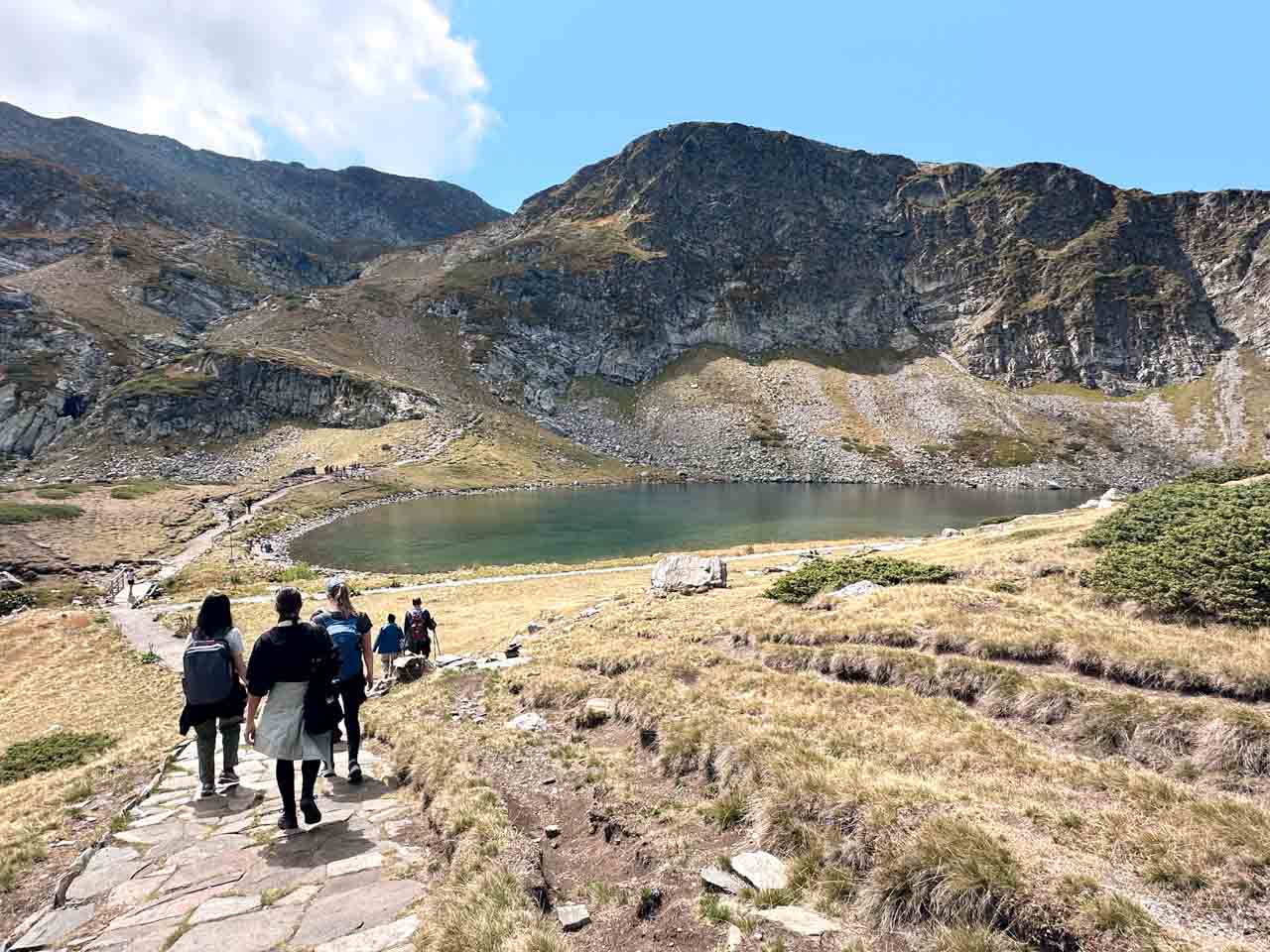 Hikers walking down a mountain trail towards one of the Seven Rila Lakes in Bulgaria&rsquo;s Rila Mountains