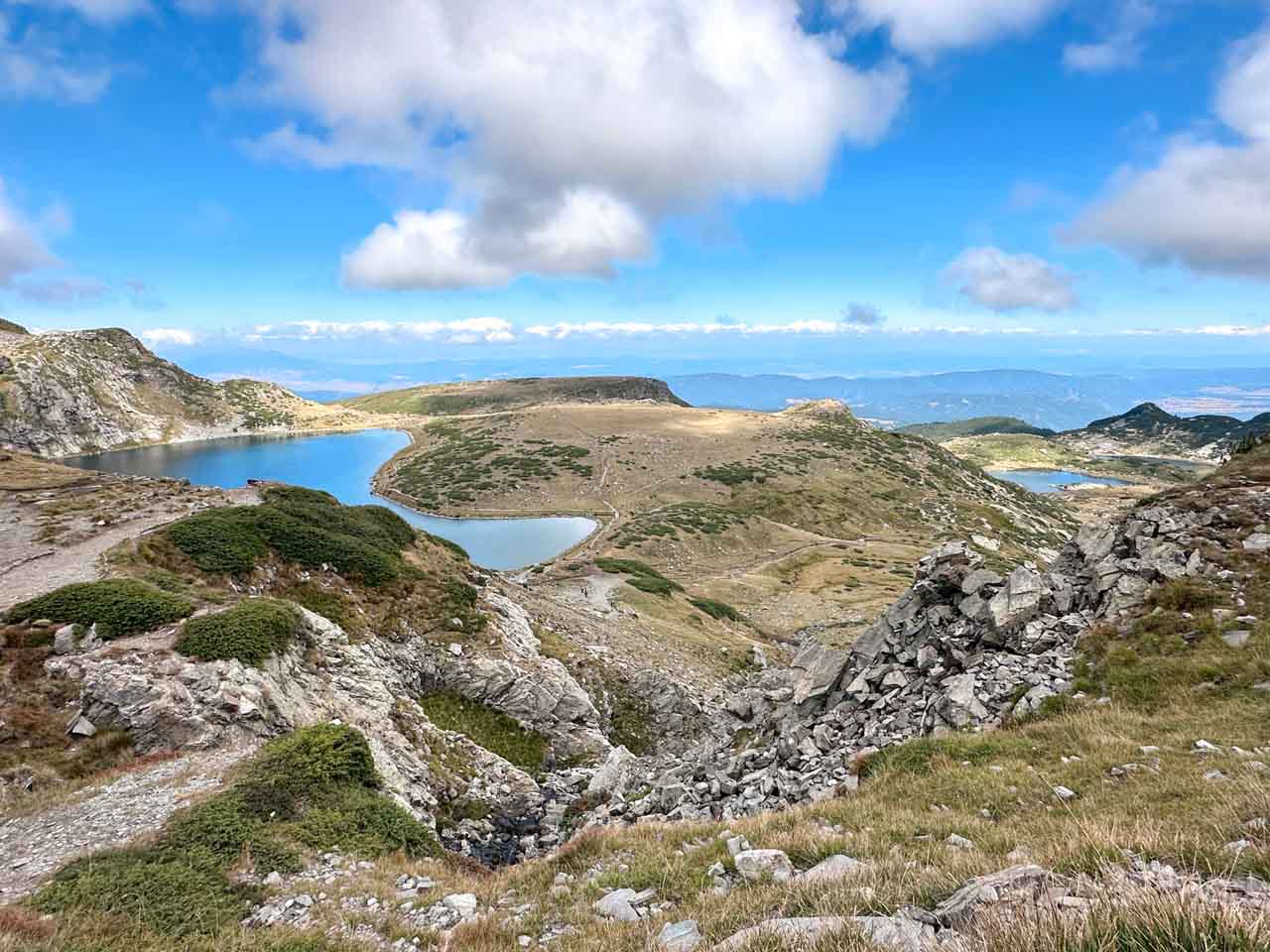 Panoramic view of some of the Seven Rila Lakes surrounded by rocky slopes beneath a blue sky