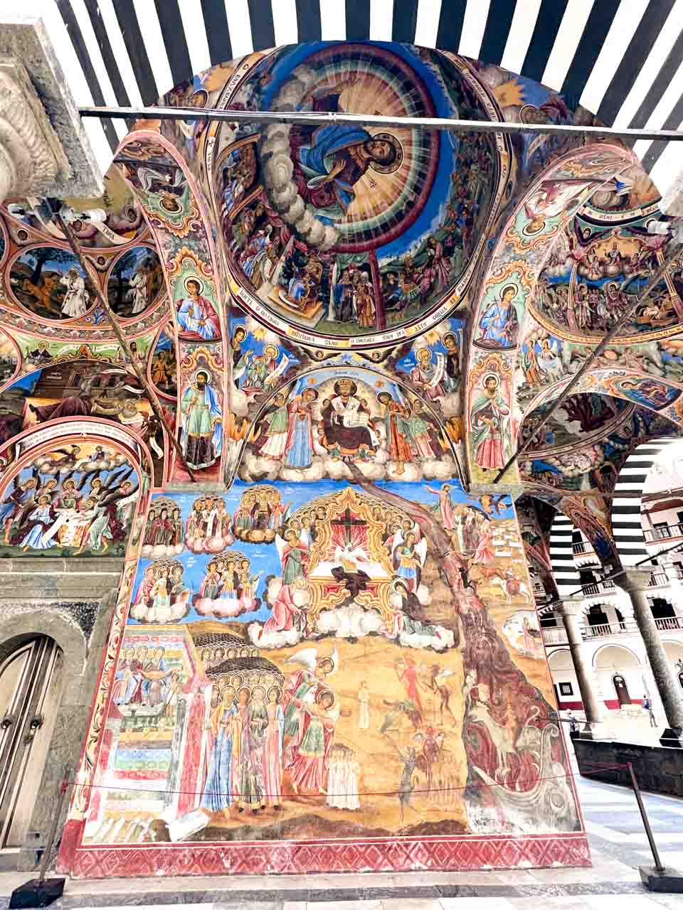 Colourful Orthodox frescoes covering the walls and arches outside the church at Rila Monastery in Bulgaria