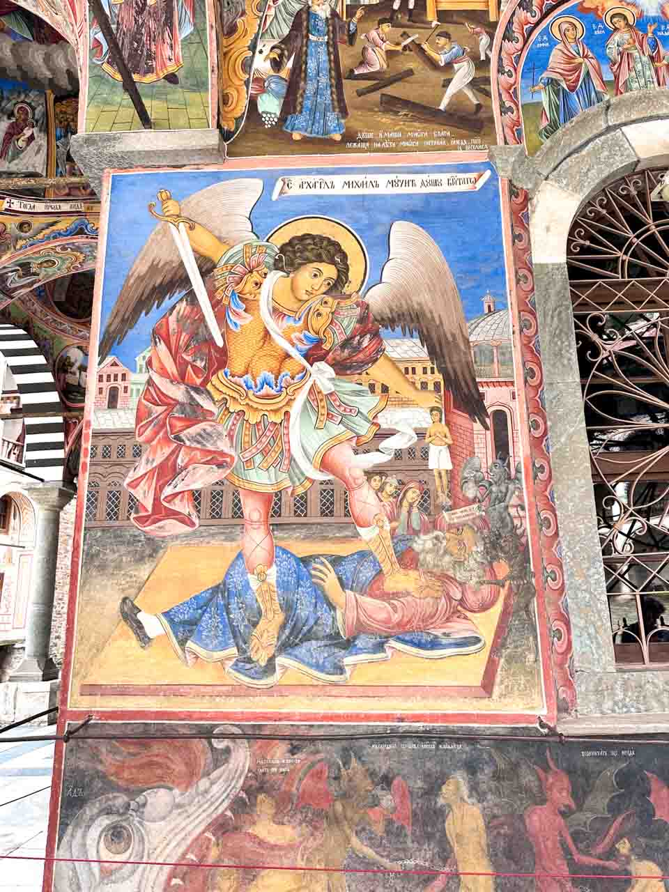 Colourful fresco of Archangel Michael defeating a fallen figure outside the church at Rila Monastery