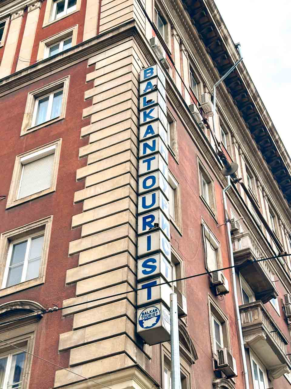 Balkan Tourist sign on the corner of a red and cream historic building in central Sofia, Bulgaria