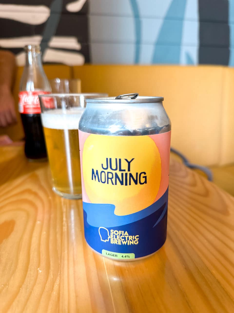 A can of July Morning lager from Sofia Electric Brewing, with a glass of beer in the background at Skapto in Sofia