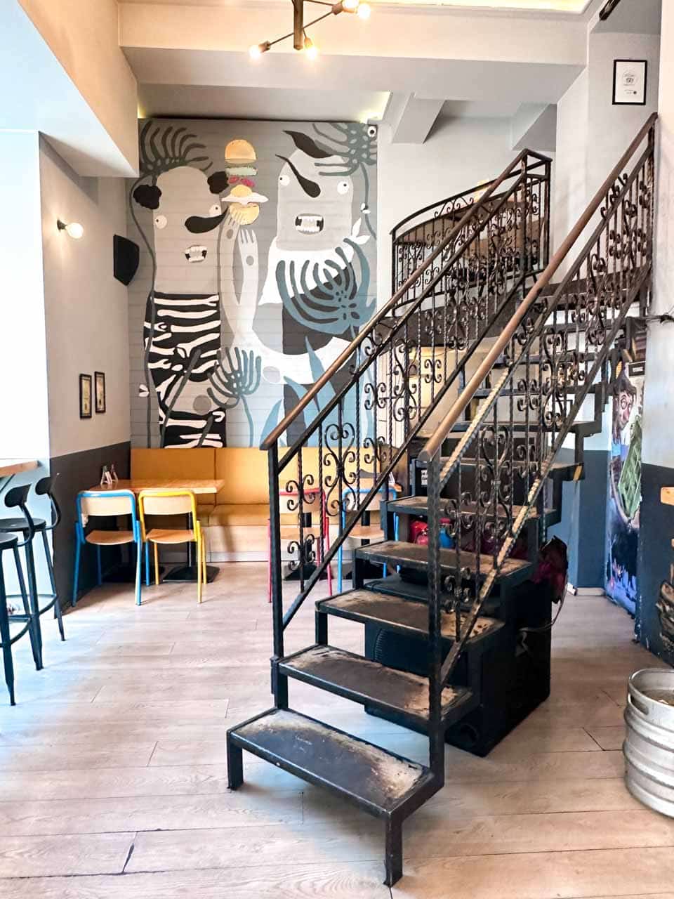 The colourful interior of Skapto in Sofia, with an ornate metal staircase and a large mural on the wall