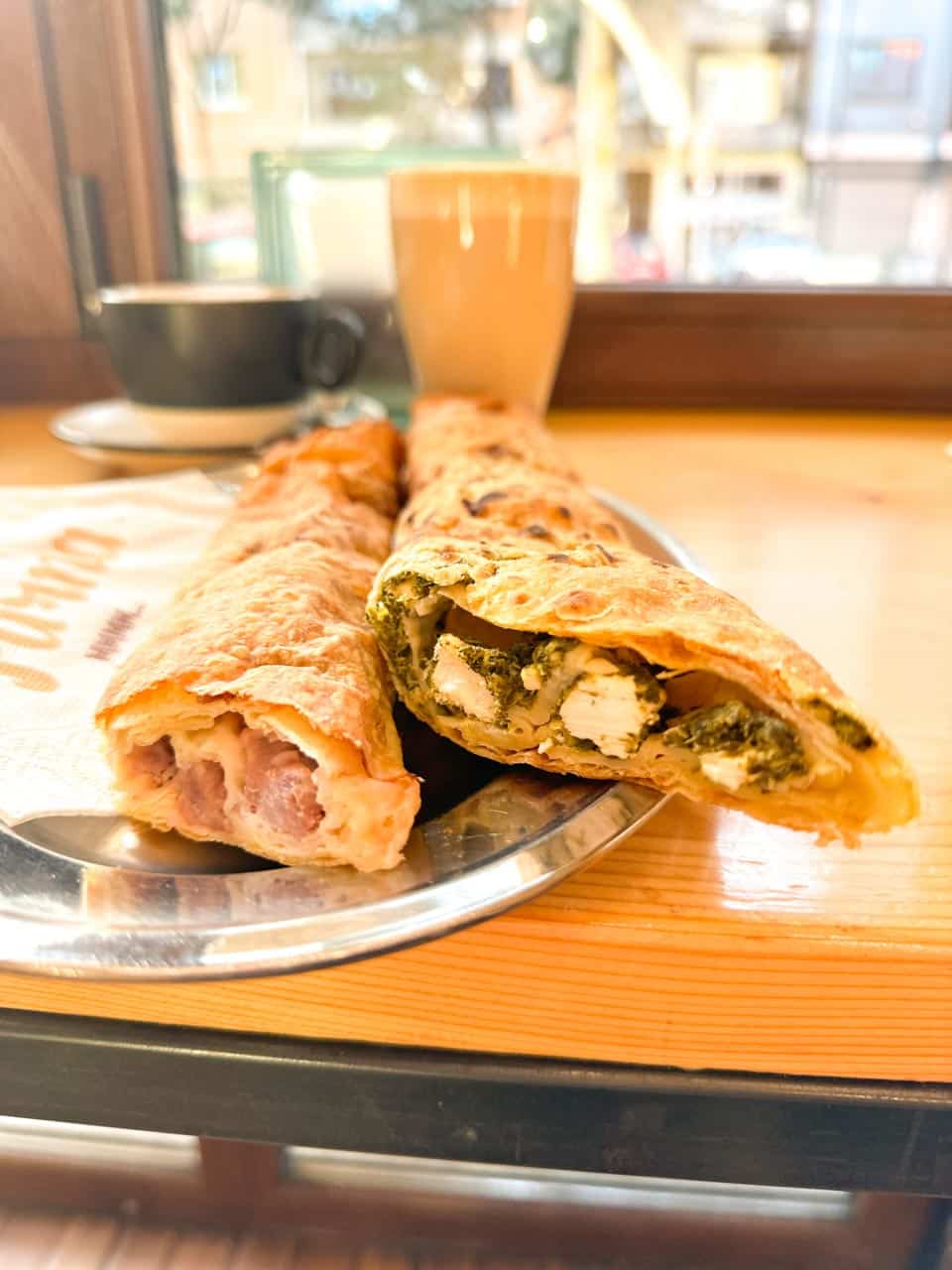 Two freshly baked banitsa pastries with different fillings, served on a metal tray at Furna bakery in Sofia