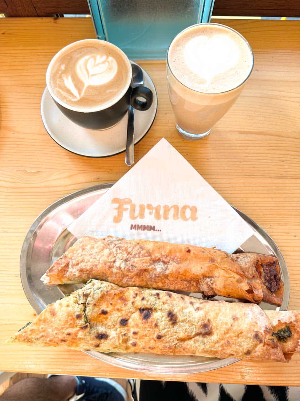 Two banitsa pastries with two coffees on a wooden table at Furna bakery in Sofia, Bulgaria