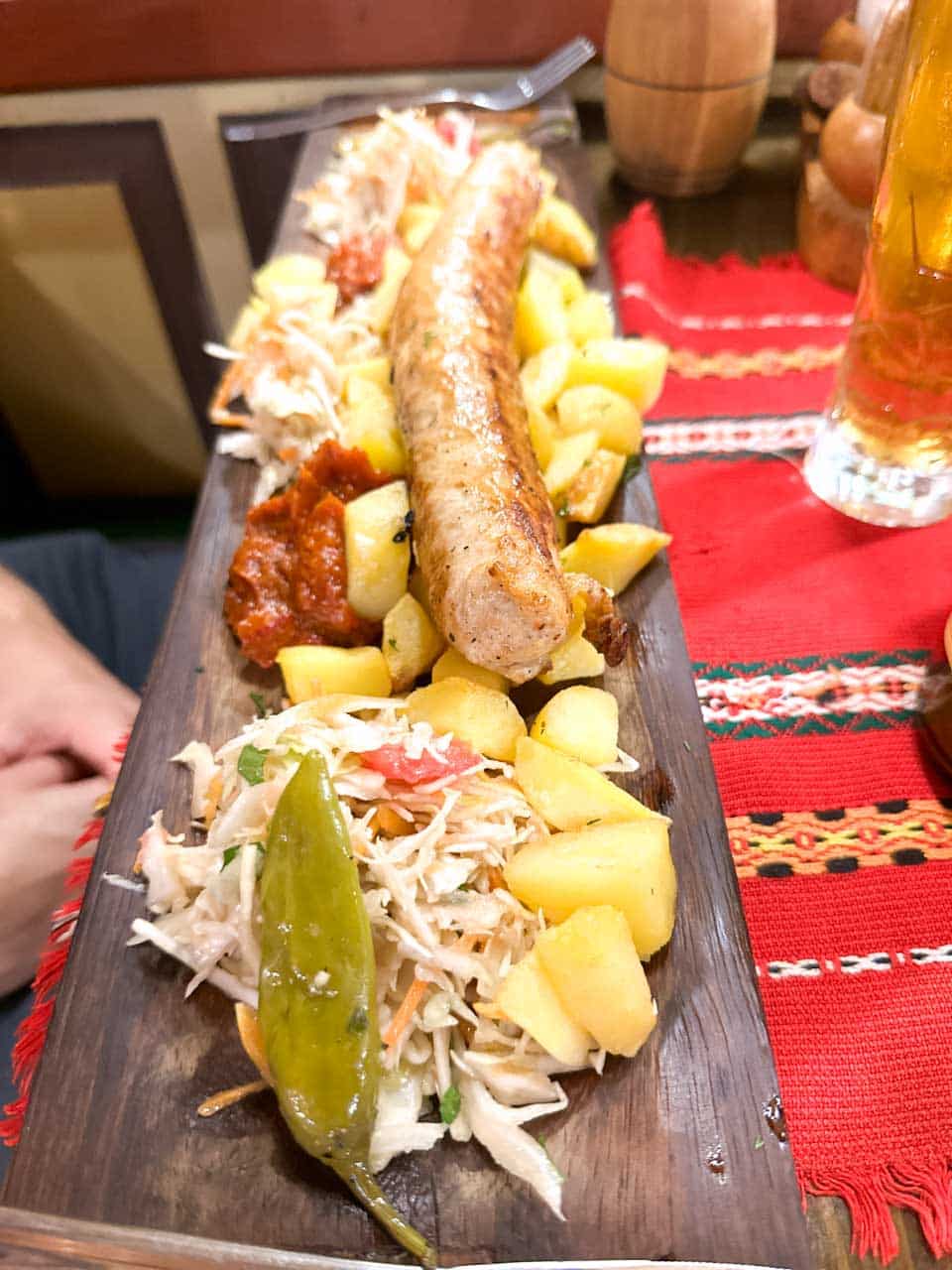 Bulgarian sausage served with potatoes, cabbage salad, roasted pepper, and lyutenitsa at Hadjidraganov's Cellars Restaurant in Sofia, Bulgaria